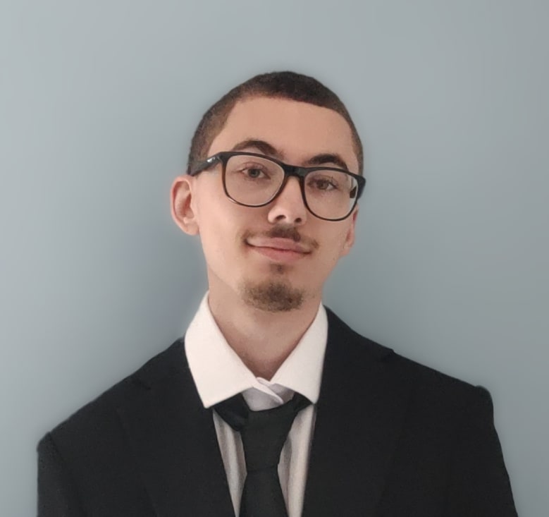 A headshot photo of Zowie in a black suit